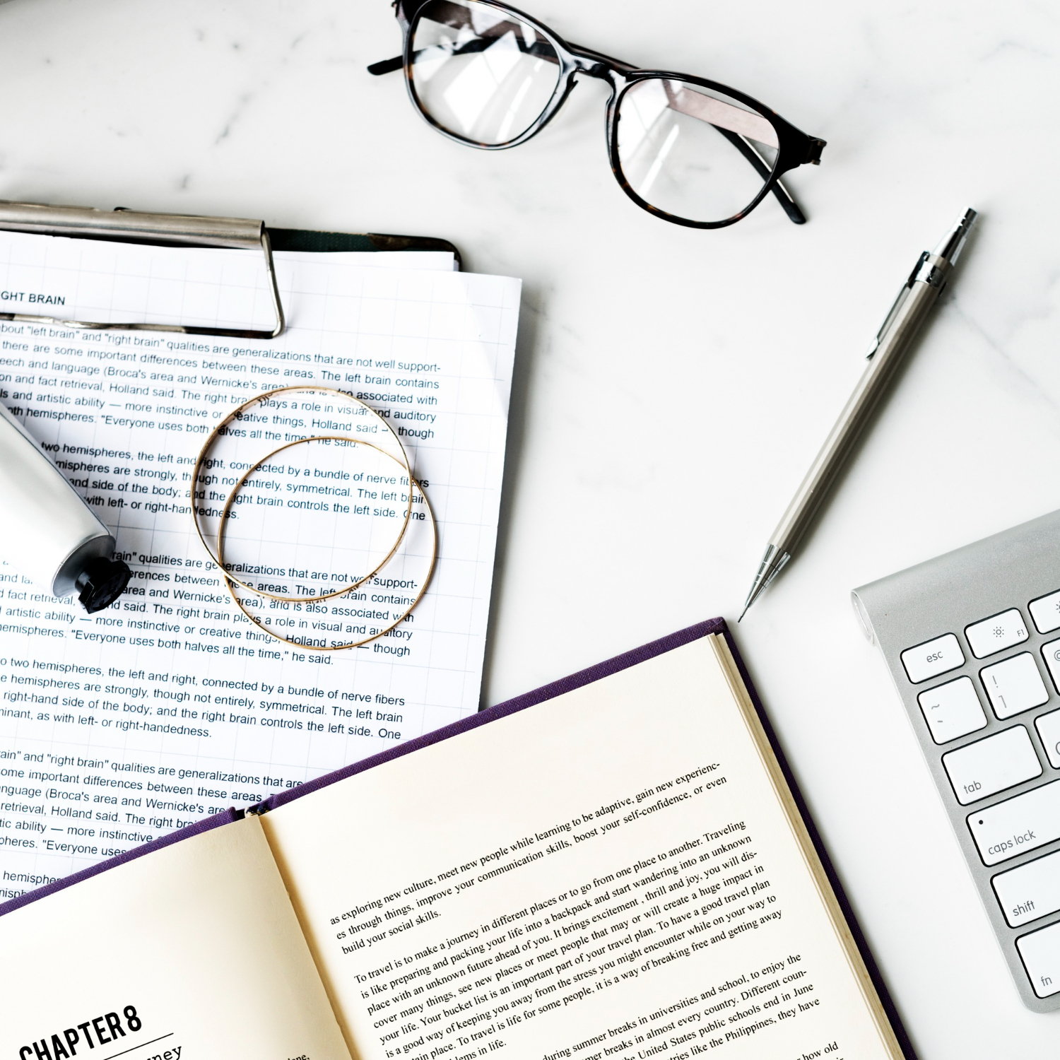 Buch, Brille, Stift und Tastatur auf einem hellen Tisch – Symbol für Ausbildung und beruflichen Werdegang in der Psychotherapie