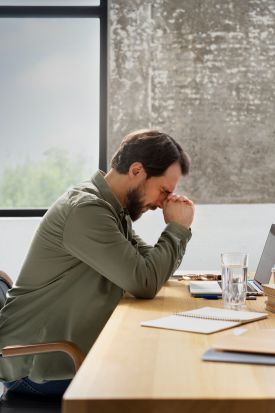Erschöpfter Mann am Schreibtisch – Burnout und Arbeitsstress, Psychotherapie in Berlin